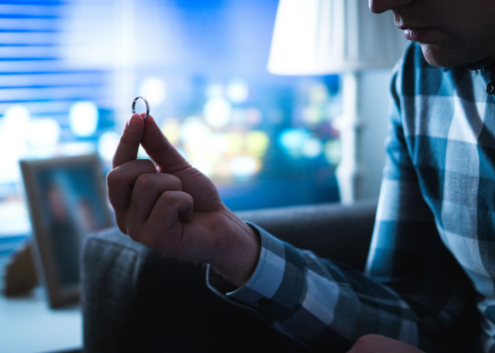 Man sitting down holding wedding ring