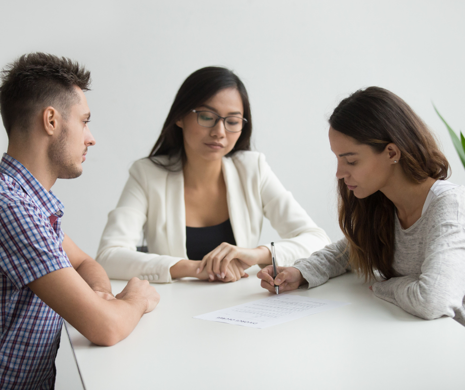 Young couple signing divorce papers in front of lawyer.