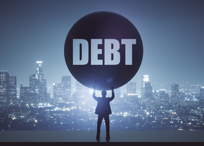 Man overlooking city and holding ball of debt.