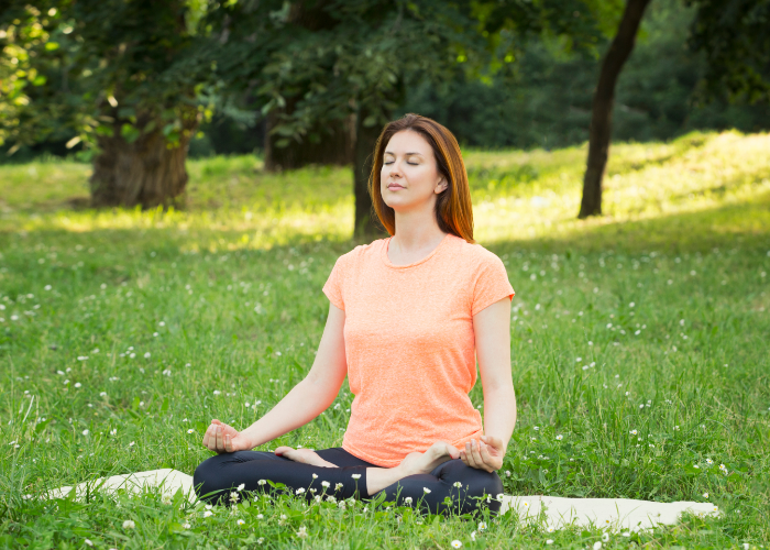 Woman sitting on grass in yoga pose.