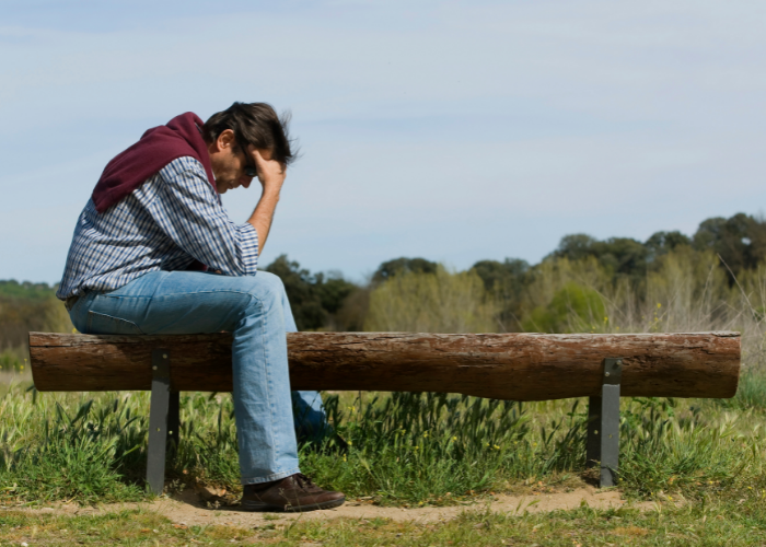 Man sitting on bench with head down.