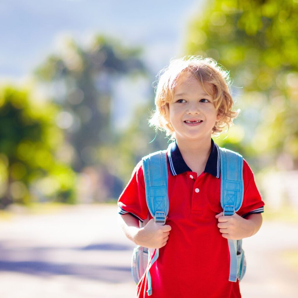 Little boy holding backpack.