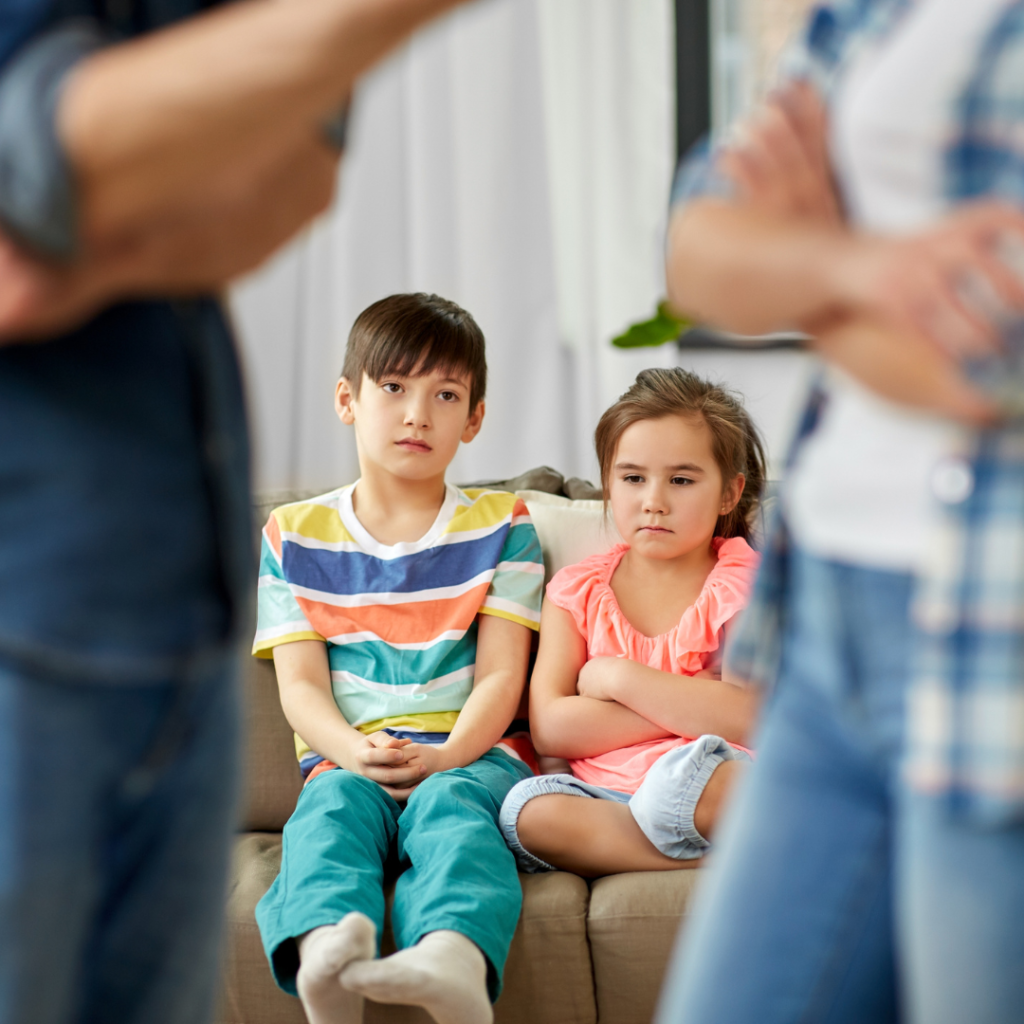 Children sitting on couch watching parents argue.