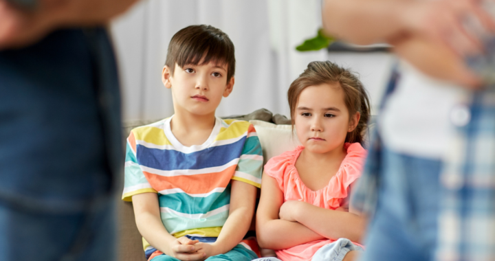 Children sitting on couch watching parents argue.
