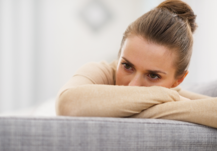 Stressed woman sittin gon couch.