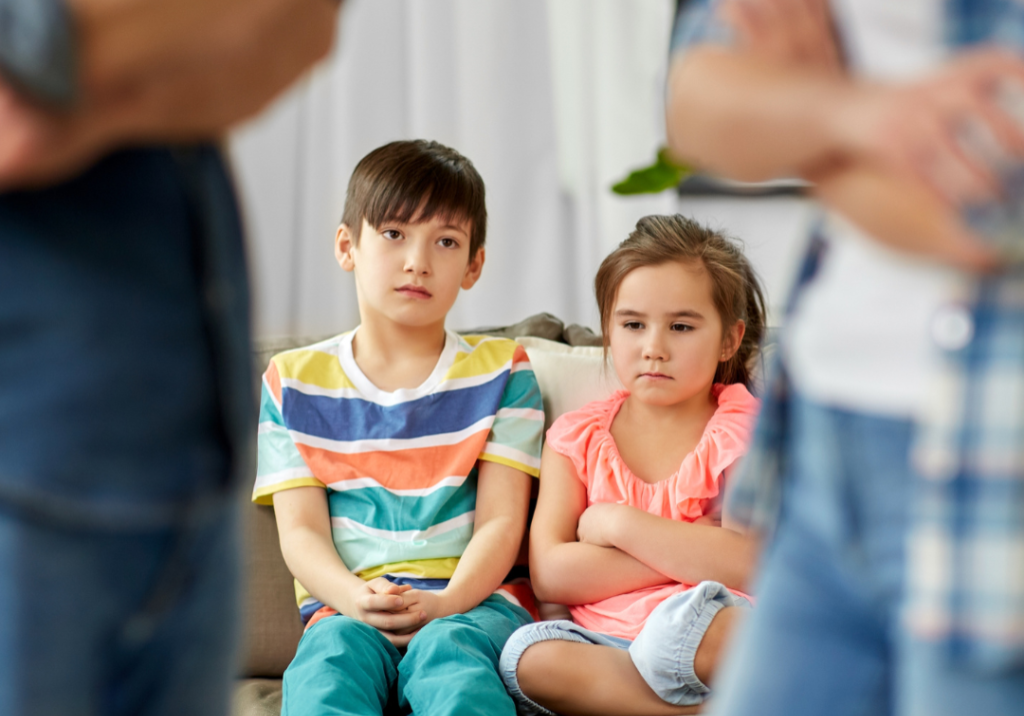 Children sitting on couch watching parents argue.