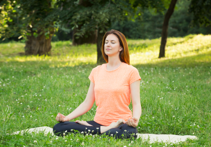 Woman sitting on grass in yoga pose.