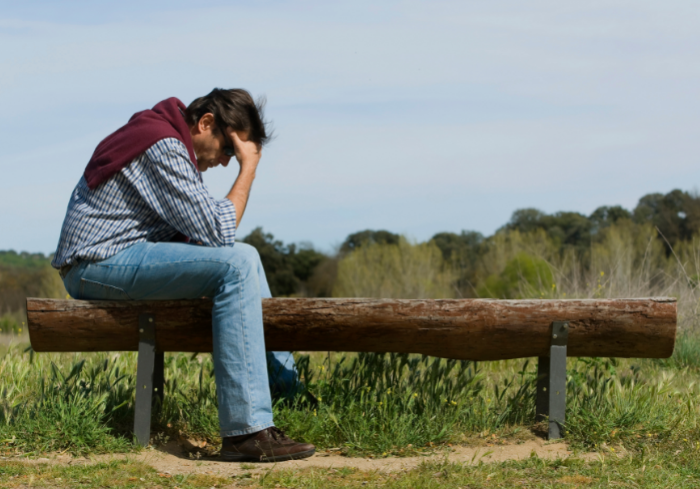 Man sitting on bench with head down.