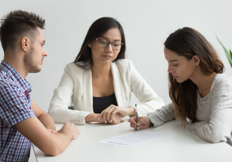 Young couple signing divorce papers in front of lawyer.
