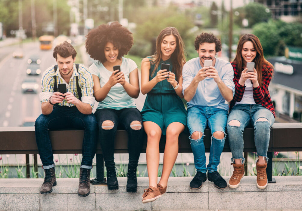 A group of friends surfing the net on a bridge.